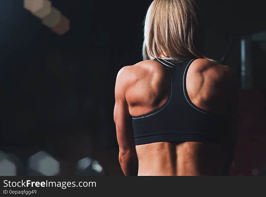 Back of blond haired female athlete in exercise clothes.