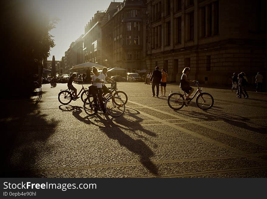 People on bicycles on city streets at sunset.