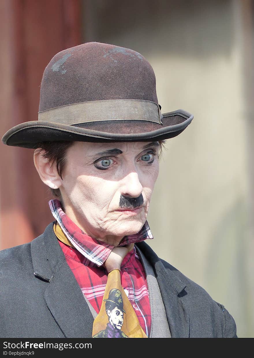 Face of street mime with hat in outdoor performance.