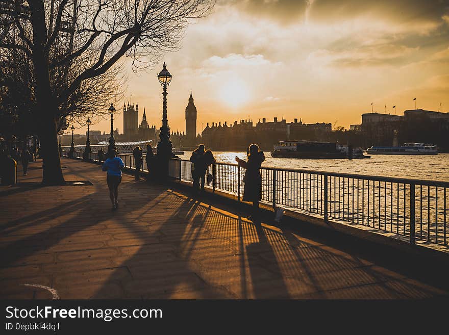 Pedestrians on waterfront along Thames River across from Westminster Abbey in London, England at sunset. Pedestrians on waterfront along Thames River across from Westminster Abbey in London, England at sunset.