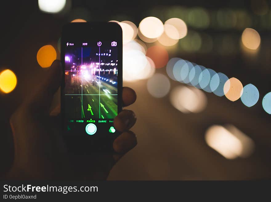 Hand holding smartphone against urban bokeh background.