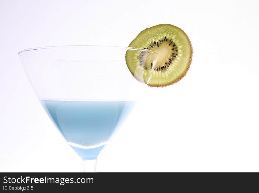 Blue liquid in martini glass garnished with slice of kiwi. Blue liquid in martini glass garnished with slice of kiwi.