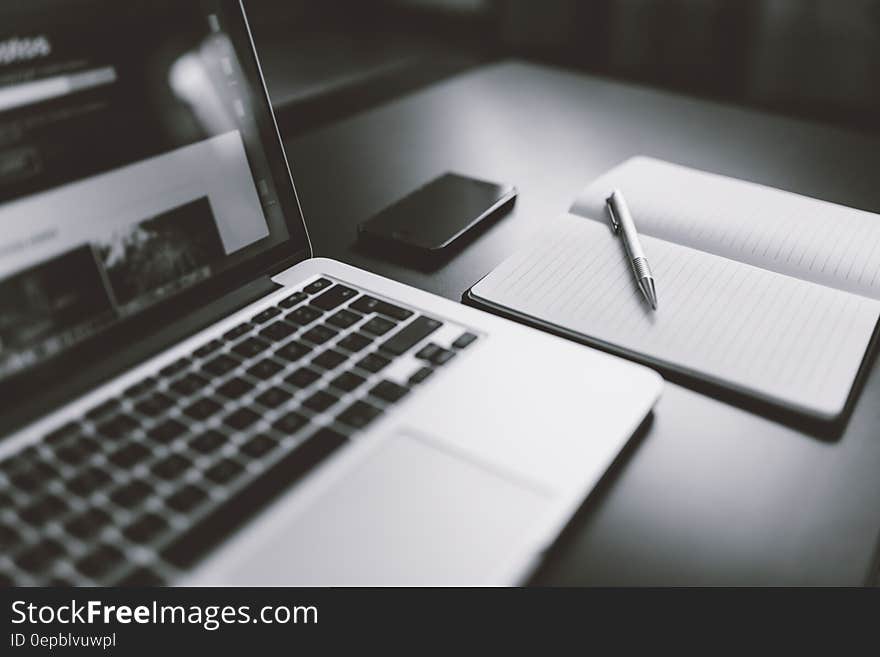 Gray Scale Photography of Macbook Iphone Notebook on Table