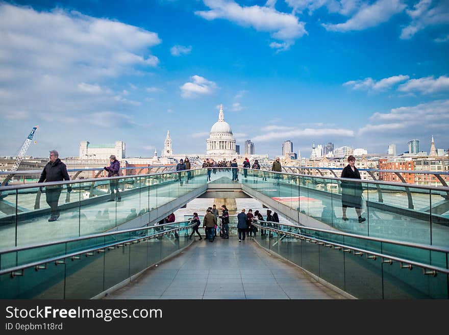 Pedestrians crossing the Millennium Bridge in London, England against blue skies on sunny day. Pedestrians crossing the Millennium Bridge in London, England against blue skies on sunny day.