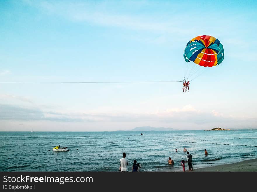 People paragliding on beach over sea during holiday or vacation.