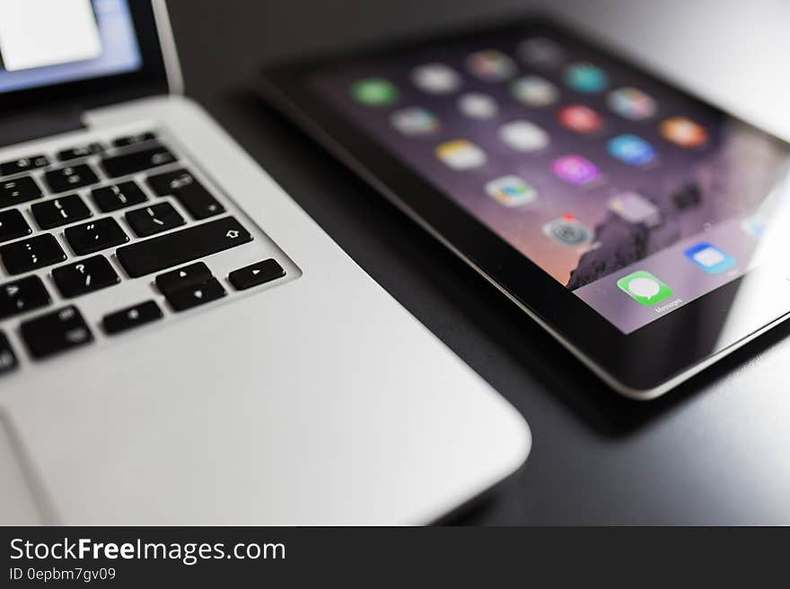 Closeup of laptop computer keyboard next to tablet with application icons. Closeup of laptop computer keyboard next to tablet with application icons.