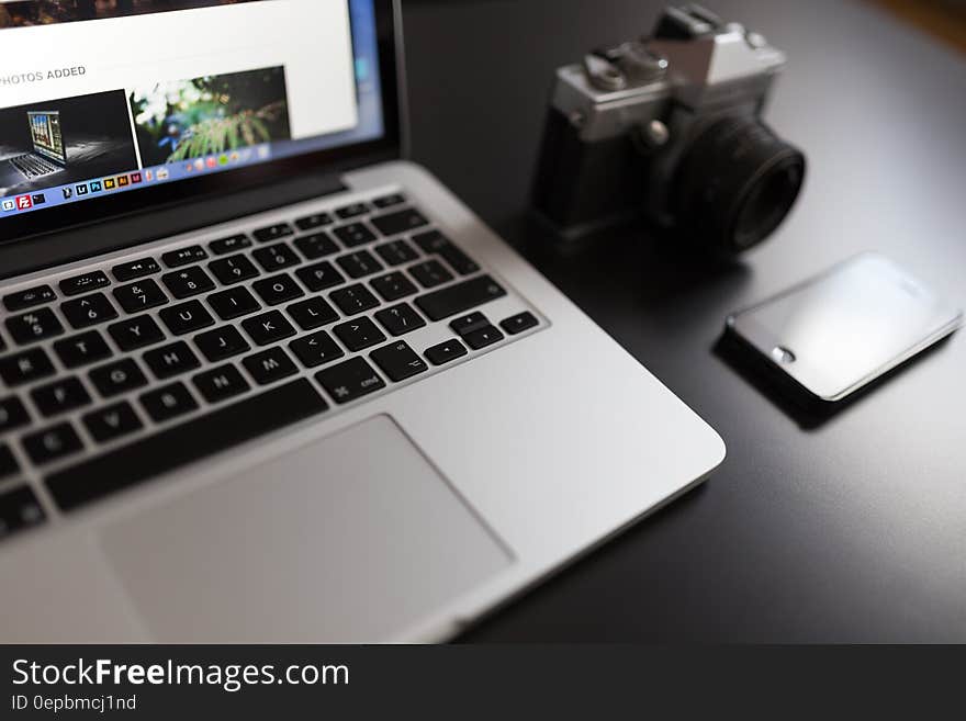 Silver Laptop Computer Beside of White and Black Camera and Black Iphone