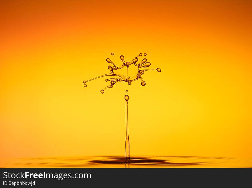 Close up of water droplet splashing against orange and yellow background. Close up of water droplet splashing against orange and yellow background.