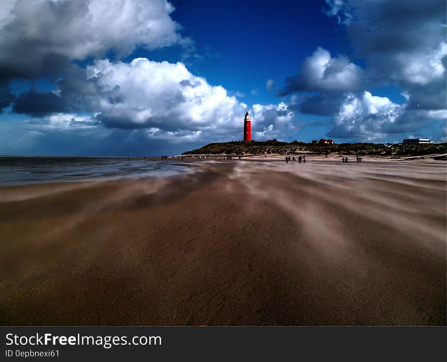 Lighthouse on sandy beach against blue skies with white clouds. Lighthouse on sandy beach against blue skies with white clouds.