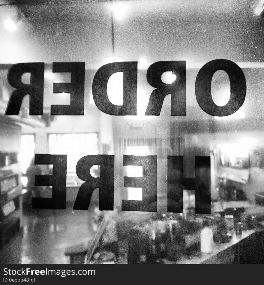 A view through a cafeteria window in black and white with the text "order here".