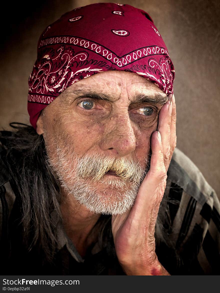 Suntanned man in old jacket wearing red bandanna with sad expression. Suntanned man in old jacket wearing red bandanna with sad expression.