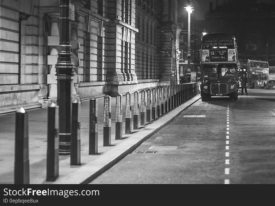 London double deck bus stopped in marked parking bay at night beside historic stone building. London double deck bus stopped in marked parking bay at night beside historic stone building.