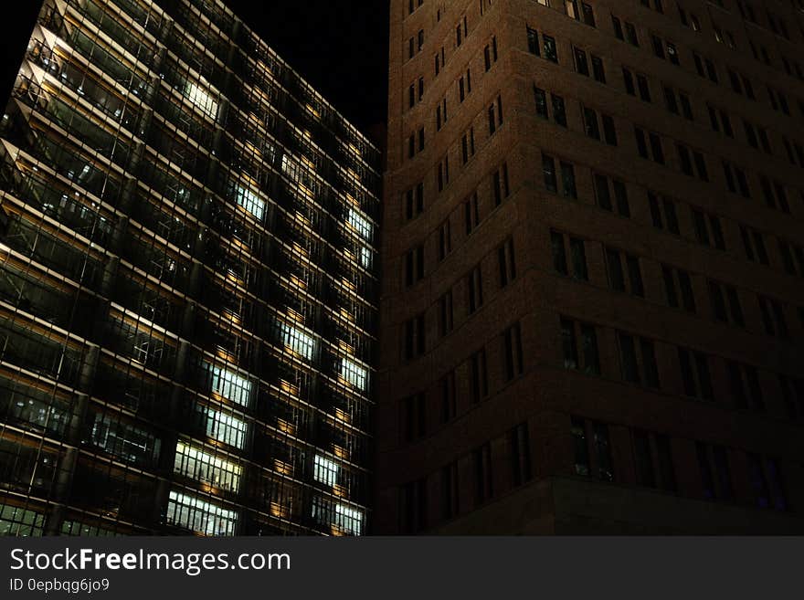 Brown Concrete Building Beside Black Concrete Building during Night Time