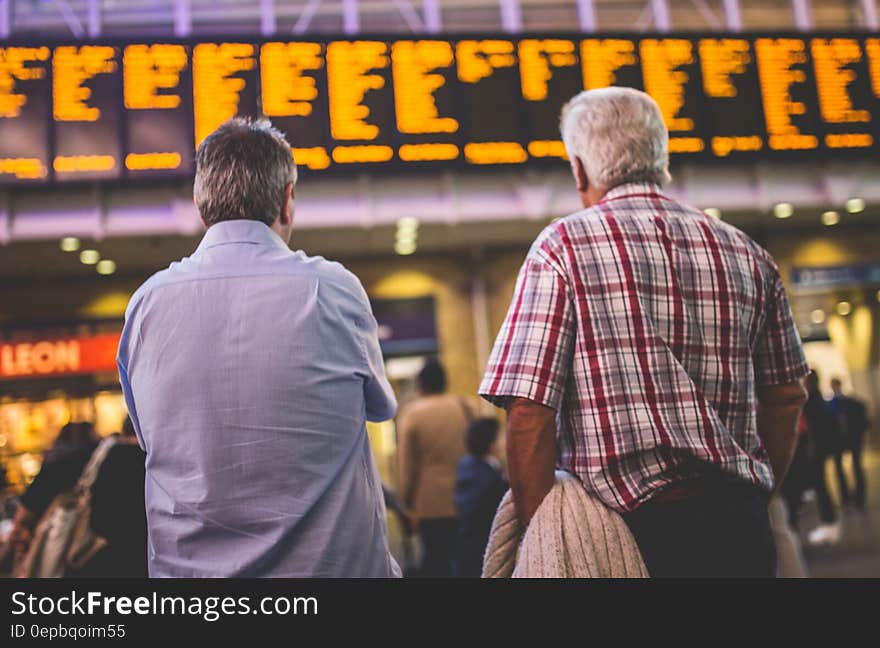 Man standing and looking at departure and arrival board inside modern airport or train station. Man standing and looking at departure and arrival board inside modern airport or train station.