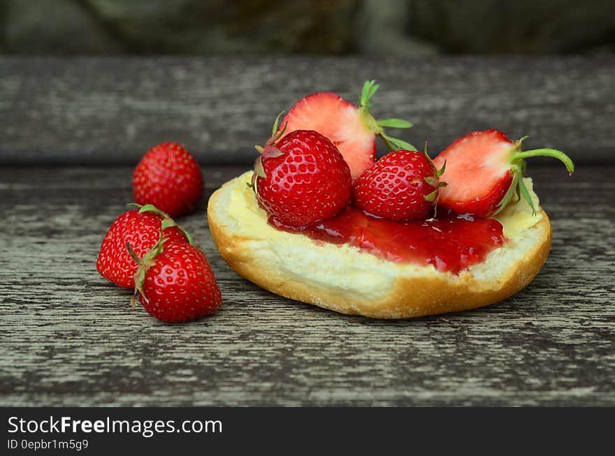 Fresh whole and cut strawberries on jam over bread on wooden tabletop. Fresh whole and cut strawberries on jam over bread on wooden tabletop.