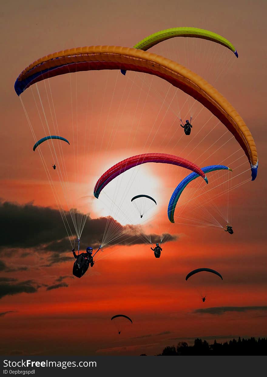 People Riding Parachutes during Sunset