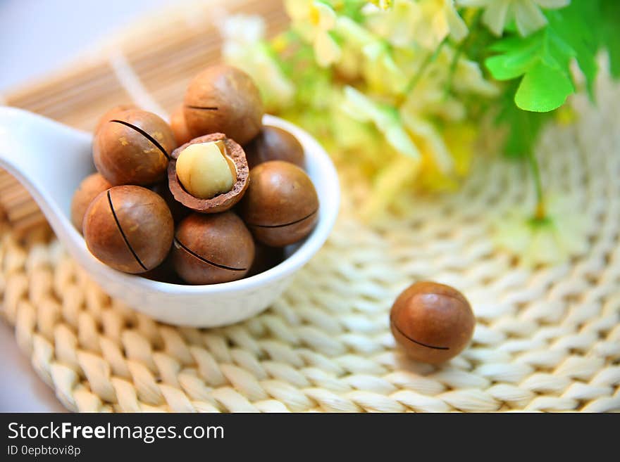 Close up of macadamia nuts in shells in white bowl on kitchen mat. Close up of macadamia nuts in shells in white bowl on kitchen mat.