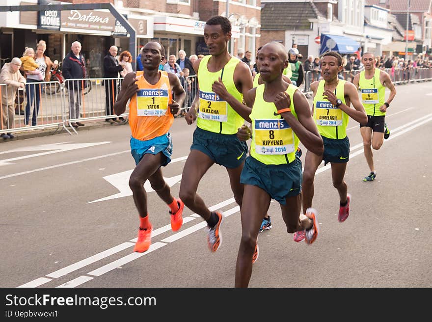 Marathon runners in pack on road race on sunny day.