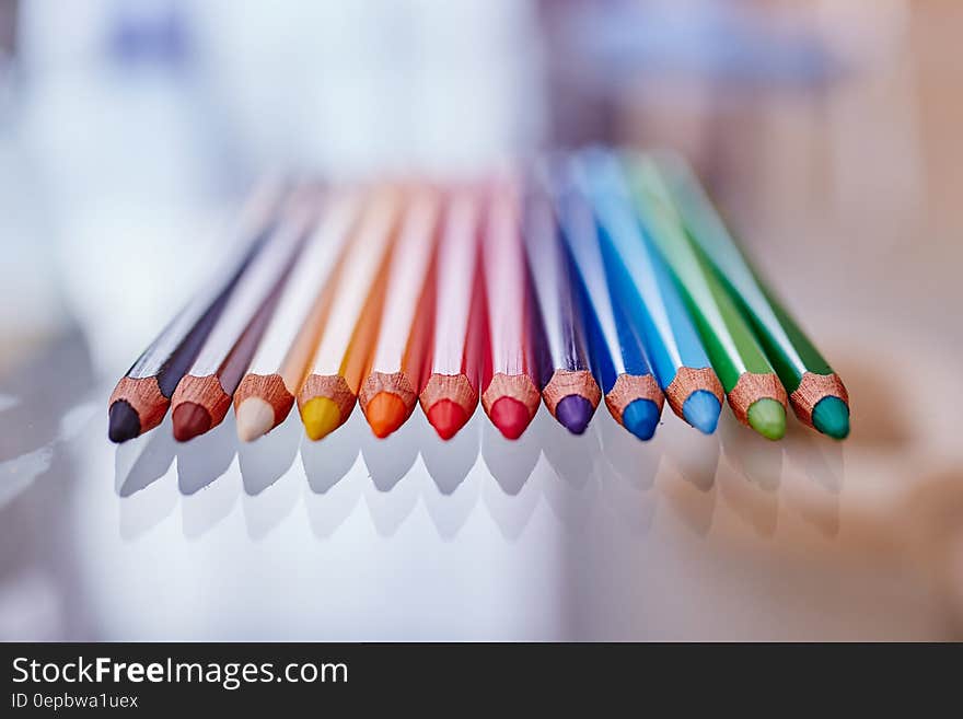 Row of colored pencil tips on glass table. Row of colored pencil tips on glass table.