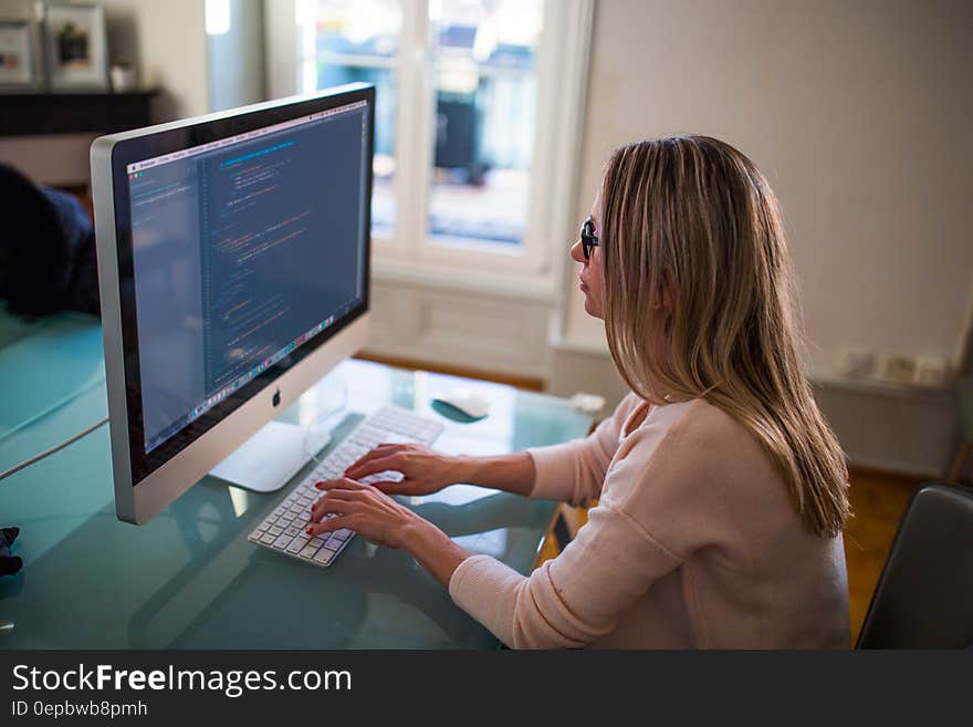 Woman typing on keyboard working at desktop computer by sunny window. Woman typing on keyboard working at desktop computer by sunny window.