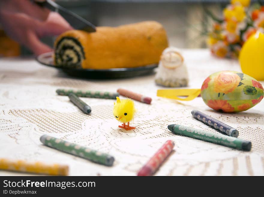 Table with crayons and decorated Easter egg with chick toy and dessert roll. Table with crayons and decorated Easter egg with chick toy and dessert roll.