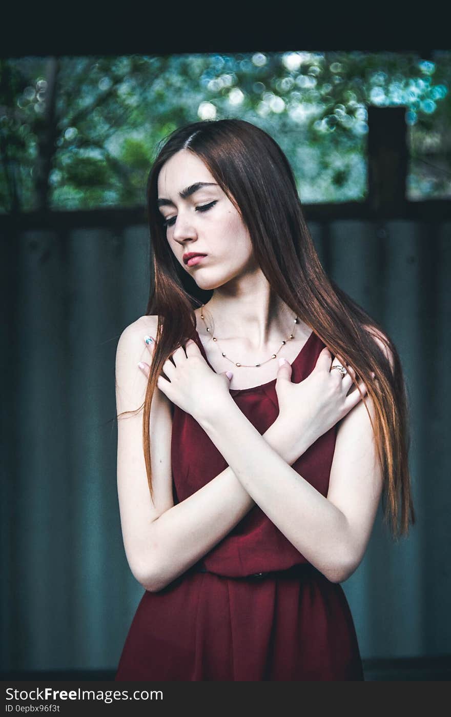 Fashionable young woman in dress with long hair and arms crossed over chest.