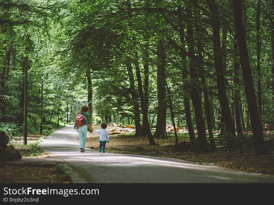 Woman Wearing Green Shirt and Red Bag Holding Children Wearing White Long Sleeve Shirt Walking