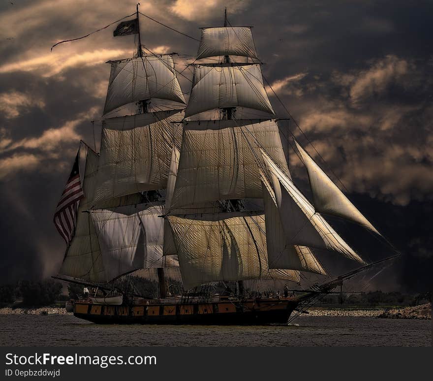 Tall sailing ship in waters along snowy coastline against stormy skies. Tall sailing ship in waters along snowy coastline against stormy skies.