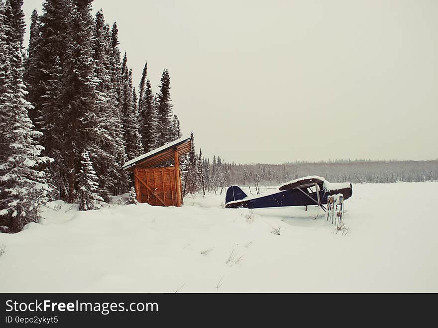 Black Aircraft Beside Brown Bunk House on Snowy Place