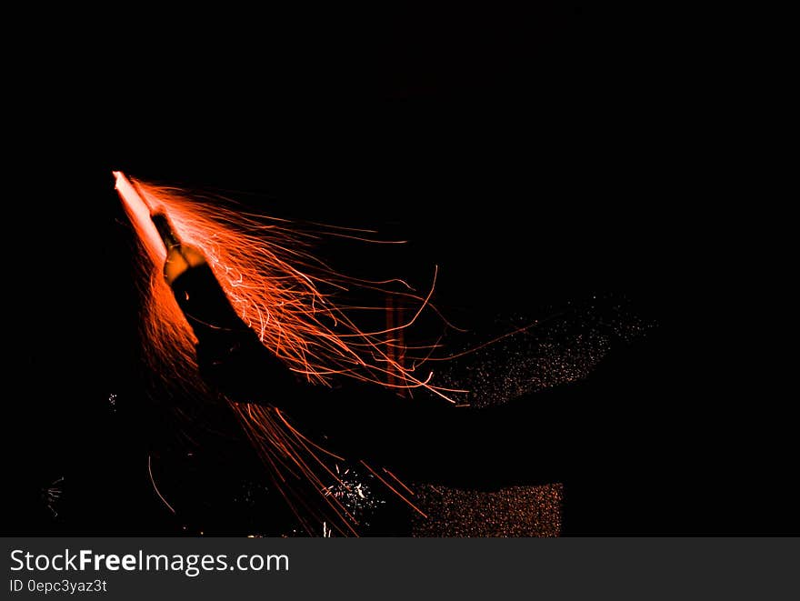 Red fireworks rocket against black night sky.