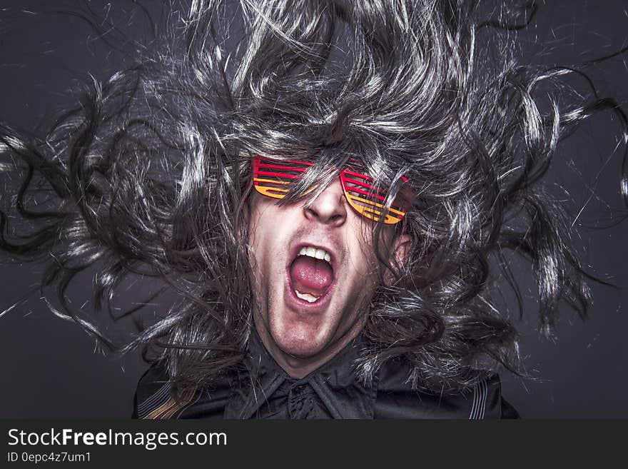 Man yelling with long grey hair wearing colorful sunglasses yelling with mouth open. Man yelling with long grey hair wearing colorful sunglasses yelling with mouth open.