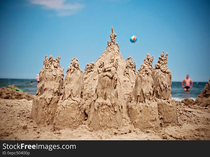 Sand Sculpture on Beach Under Blue Sky