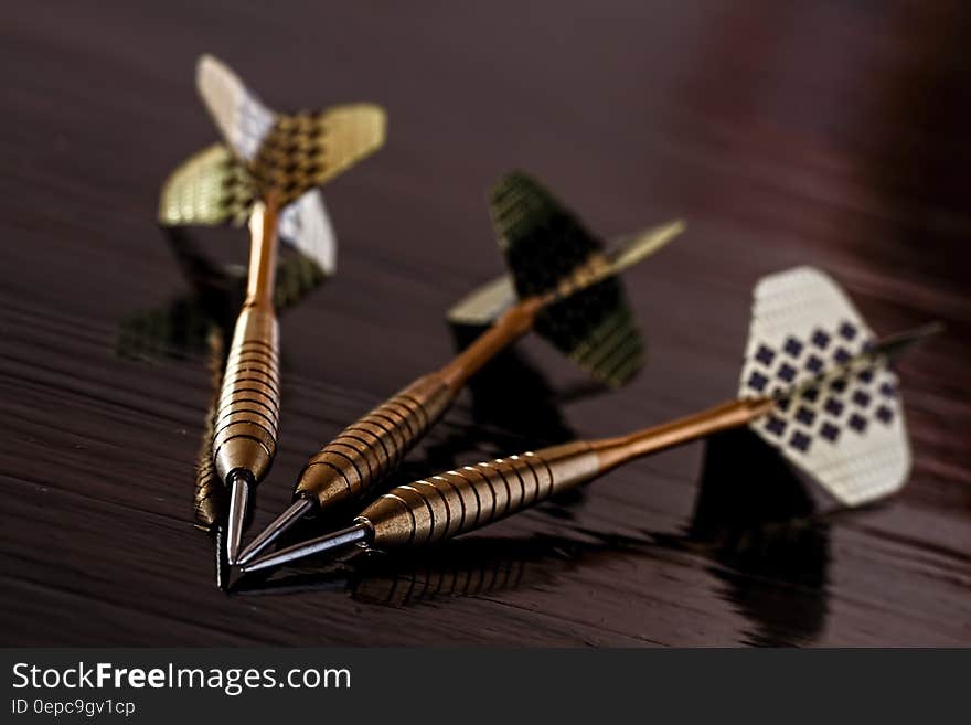 Brass Gold Darts on Brown Table