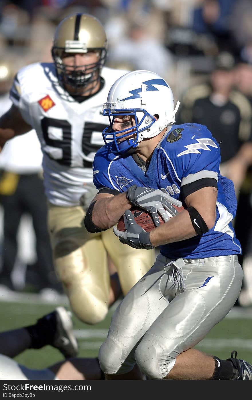 Man in Blue and Silver Football Uniform Carrying Football