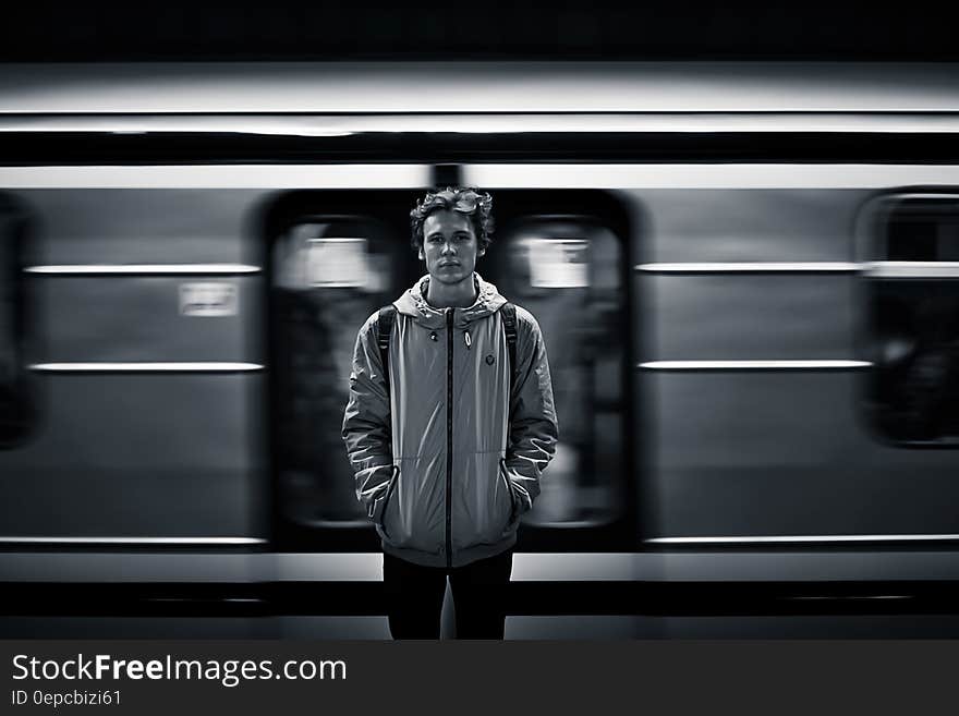 A young man standing at a metro station, a train passing behind him. A young man standing at a metro station, a train passing behind him.