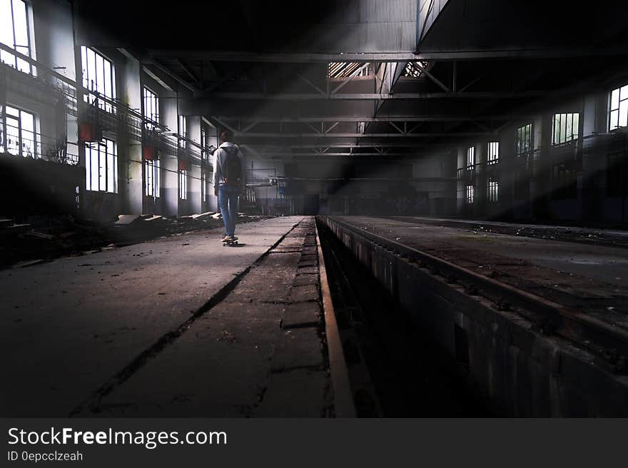 Rear view of skateboarder in abandoned urban factory building. Rear view of skateboarder in abandoned urban factory building.