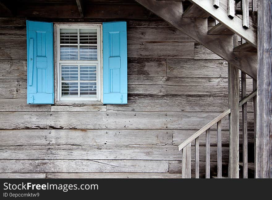 A wooden cabin with bright blue shutters on the window. A wooden cabin with bright blue shutters on the window.