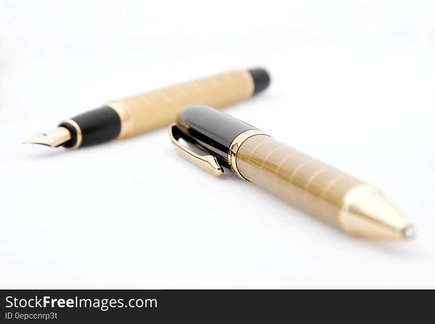 A gold pen and fountain pen on a white background.