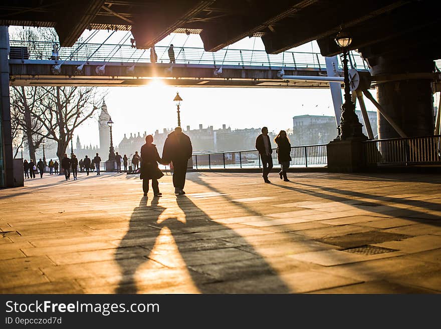 Couples walking along South Bank at sunset with the River Thames and Houses of Parliament, in London in the background. Couples walking along South Bank at sunset with the River Thames and Houses of Parliament, in London in the background.