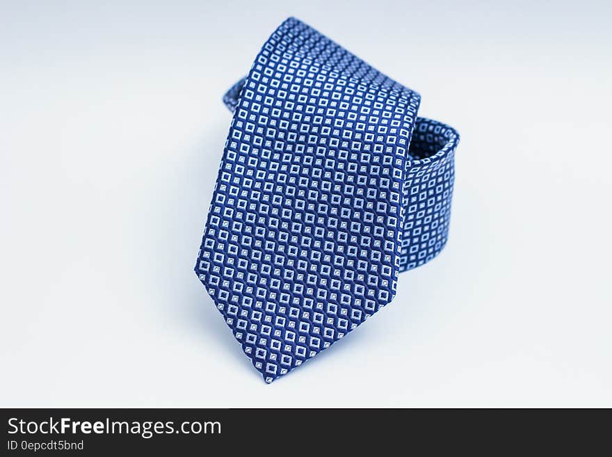 Closeup of fashionable blue silk tie with square patterns on light background.