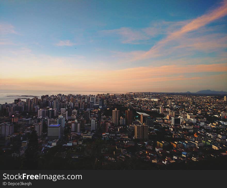 Aerial view of modern city skyline at sunset with sea in background.