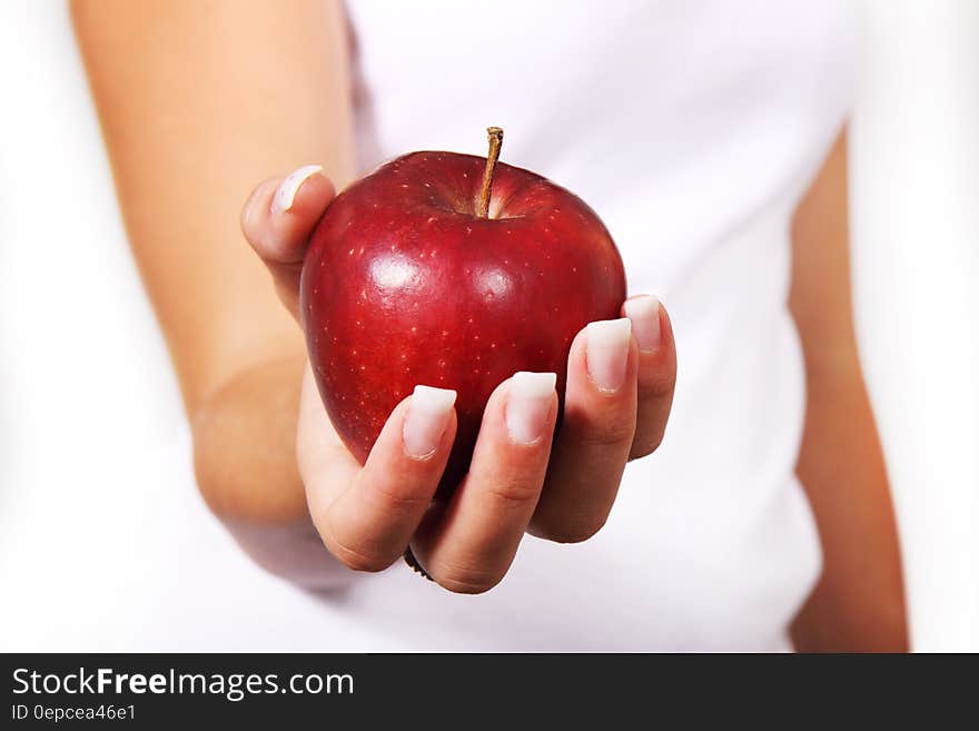 Person in White Shirt Holding Red Apple