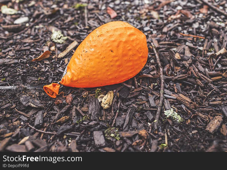 A deflated orange balloon lying on ground. A deflated orange balloon lying on ground.