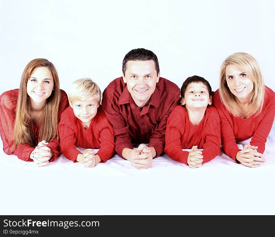 A family portrait with father, mother and three kids wearing red shirts.