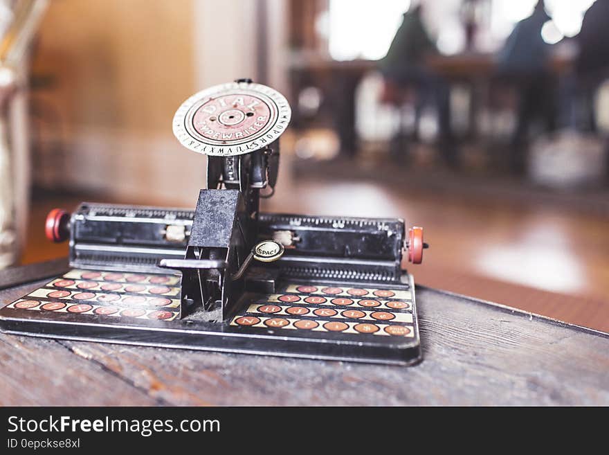 An antique dial typewriter on a wooden desk. An antique dial typewriter on a wooden desk.