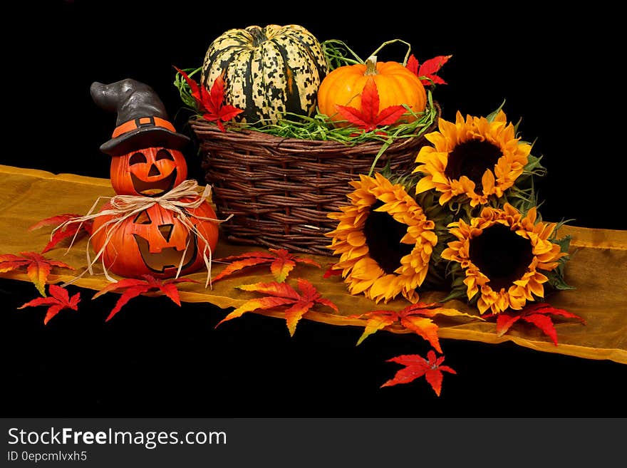 A basket of pumpkins and sunflowers with Halloween pumpkins on the side. A basket of pumpkins and sunflowers with Halloween pumpkins on the side.