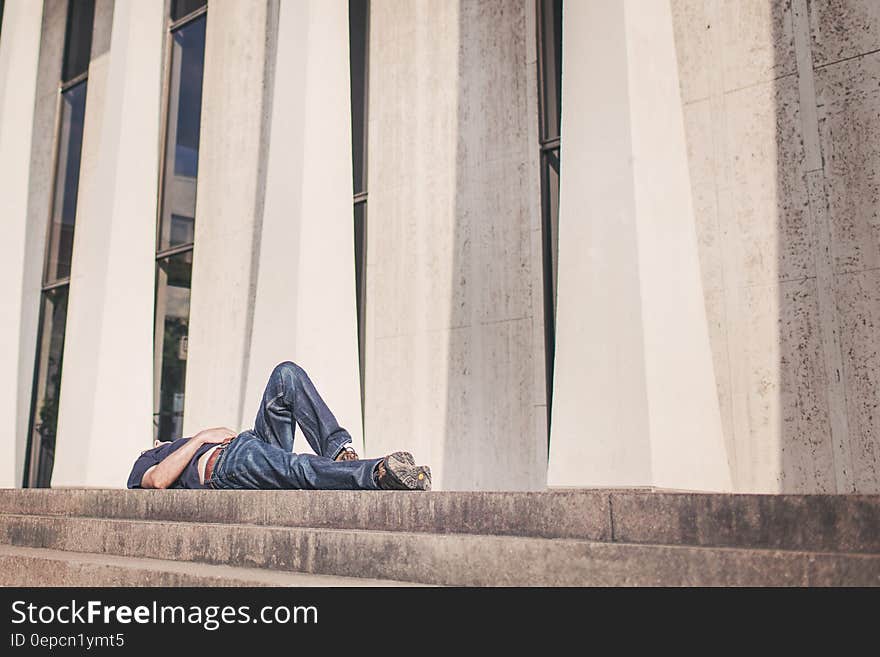 Man laying outside modern building on stone staircase on sunny day. Man laying outside modern building on stone staircase on sunny day.