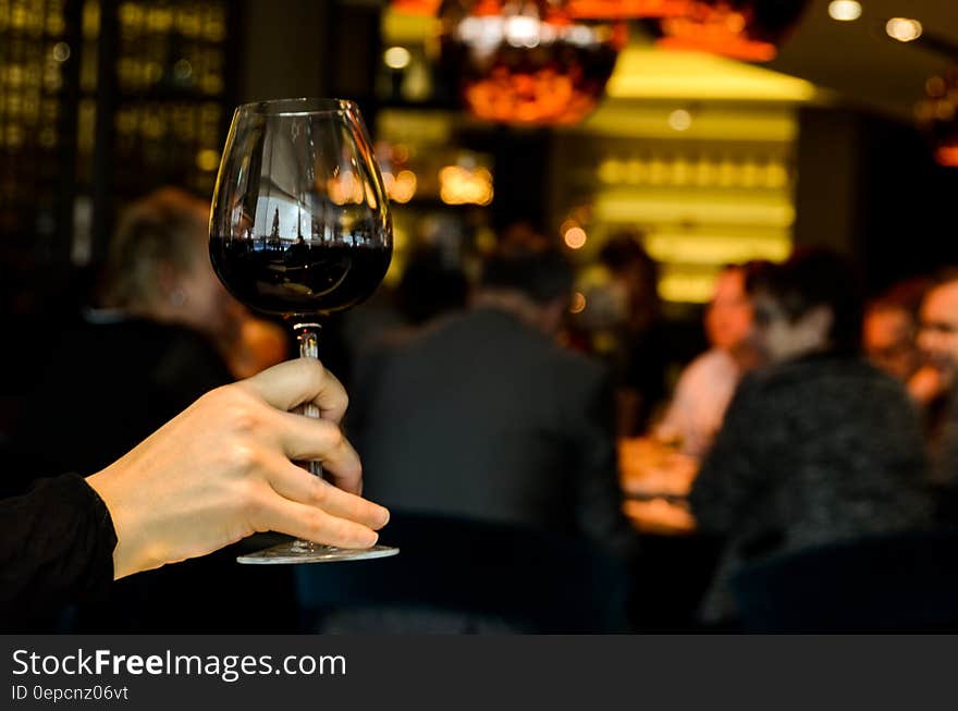 A woman holding up a full glass of red wine. A woman holding up a full glass of red wine.