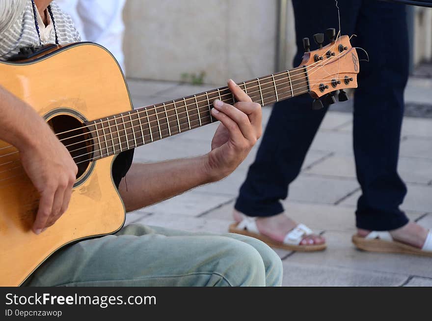 Person in Grey Shirt and Blue Denim Jeans Playing Acoustic Guitar