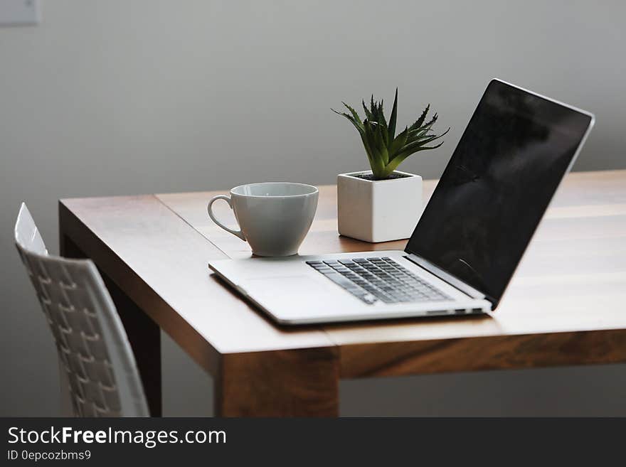 Silver Laptop Computer Next to Ceramic Cup